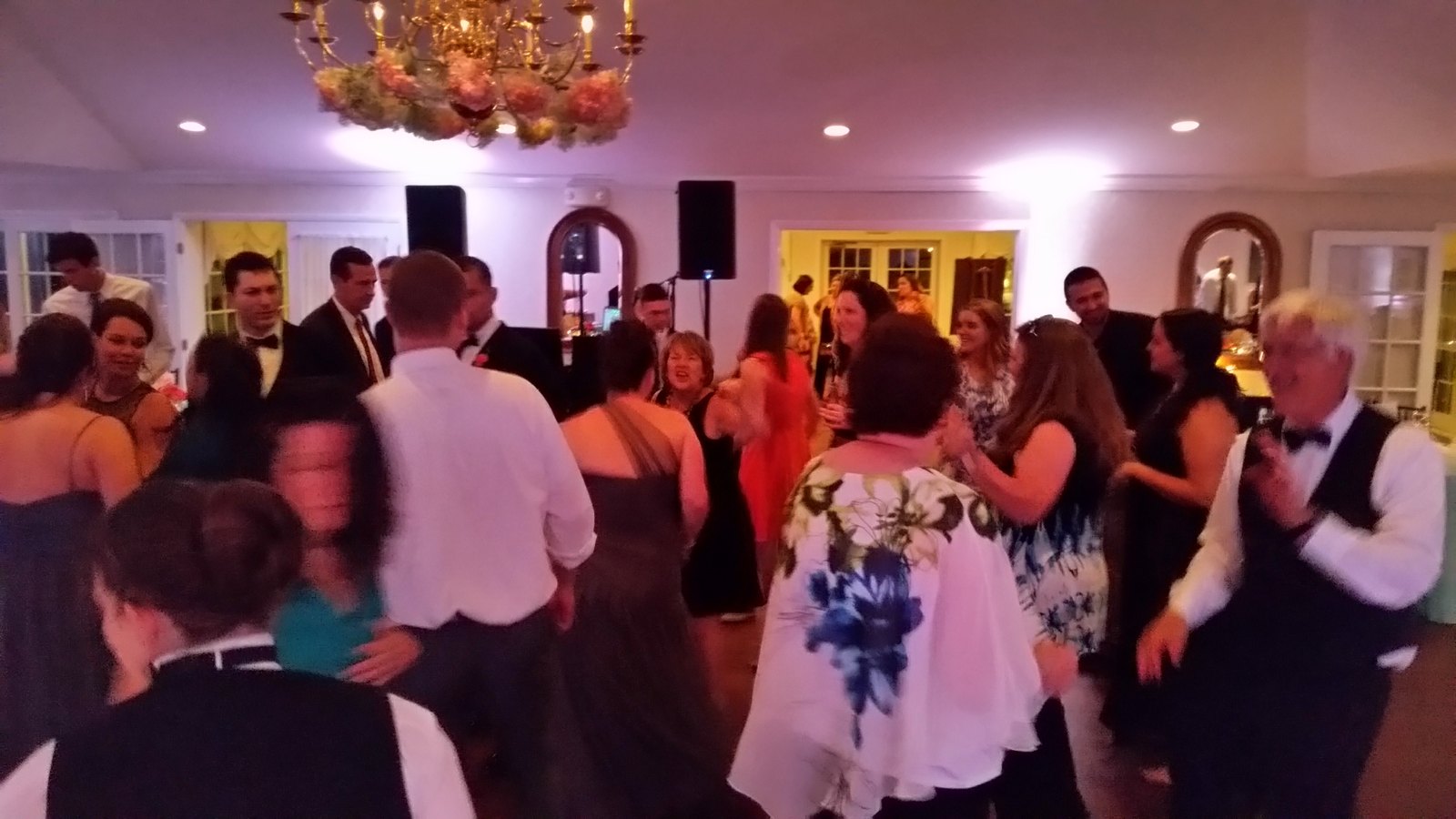 Guests dancing together under a chandelier at a reception