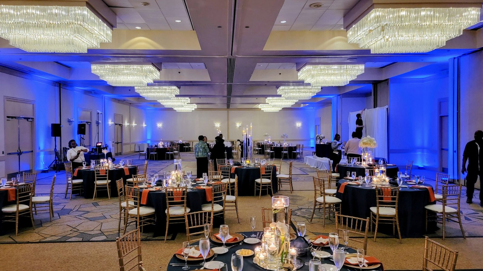 A ballroom set for a reception with blue uplighting