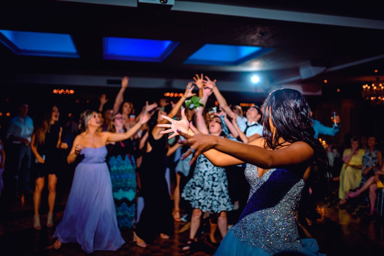 A bride tossing her bouquet to guests reaching for it