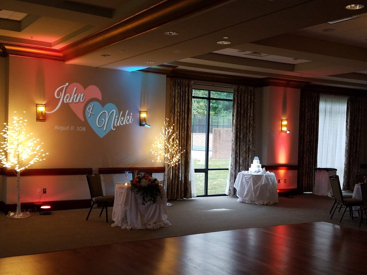 A reception room with a name monogram on the wall and warm uplighting