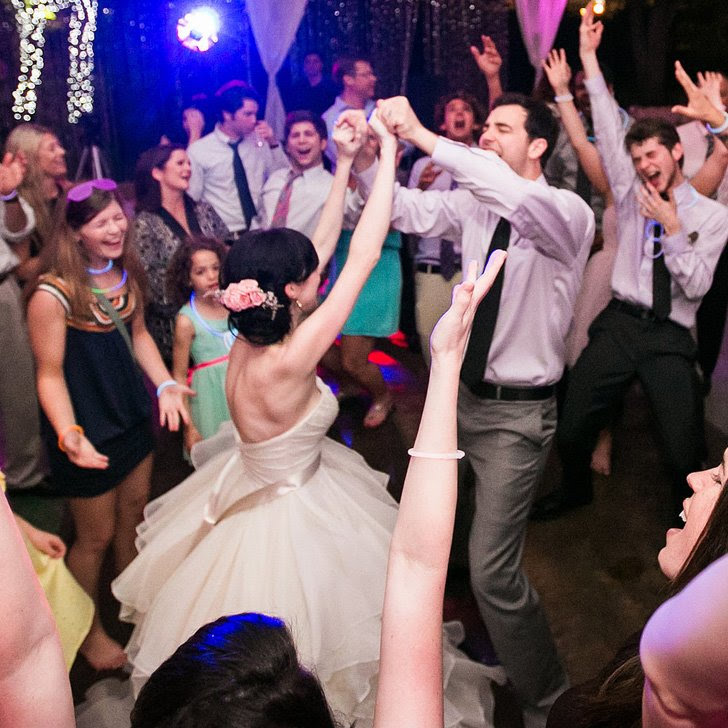 A bride spinning on the dance floor with guests cheering around her