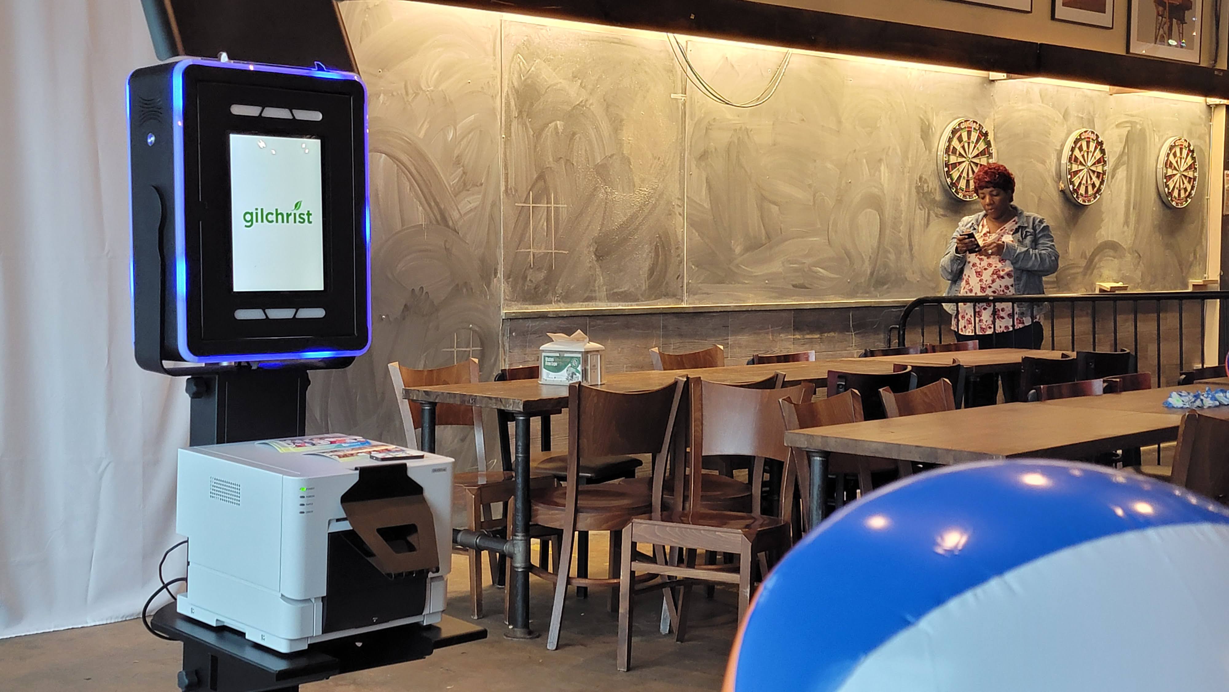 An open-air photo booth and photo printer set up beside the tables at a company event