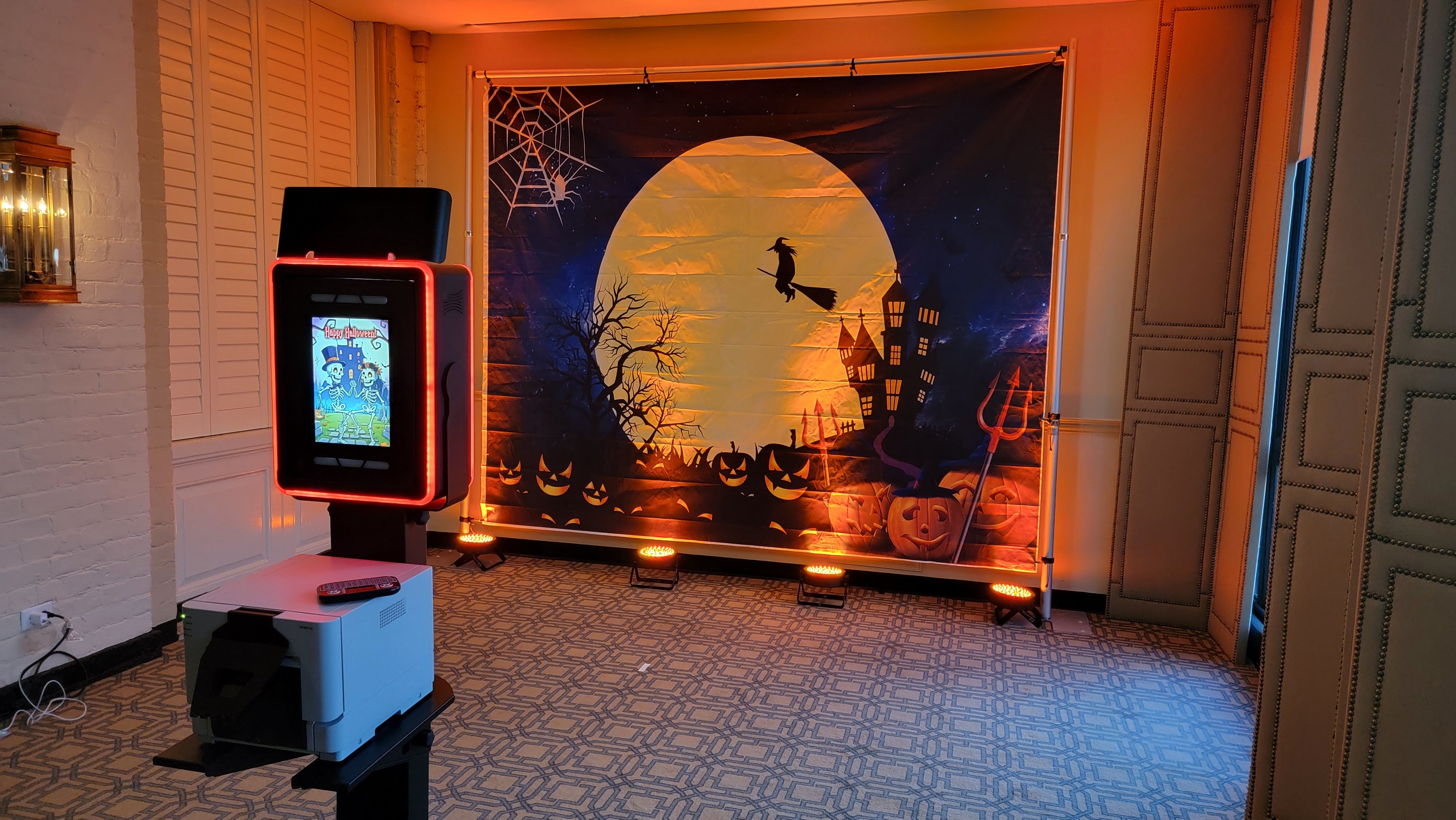 The photo booth and a Halloween backdrop set up in a ballroom, the screen showing Happy Halloween