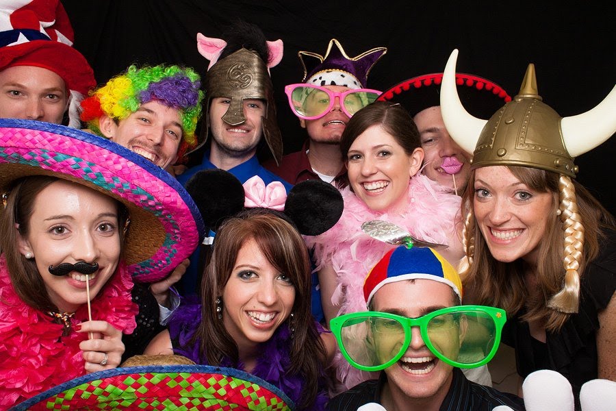 Eight friends in wigs, sombreros and a viking helmet filling the frame of one photo booth shot