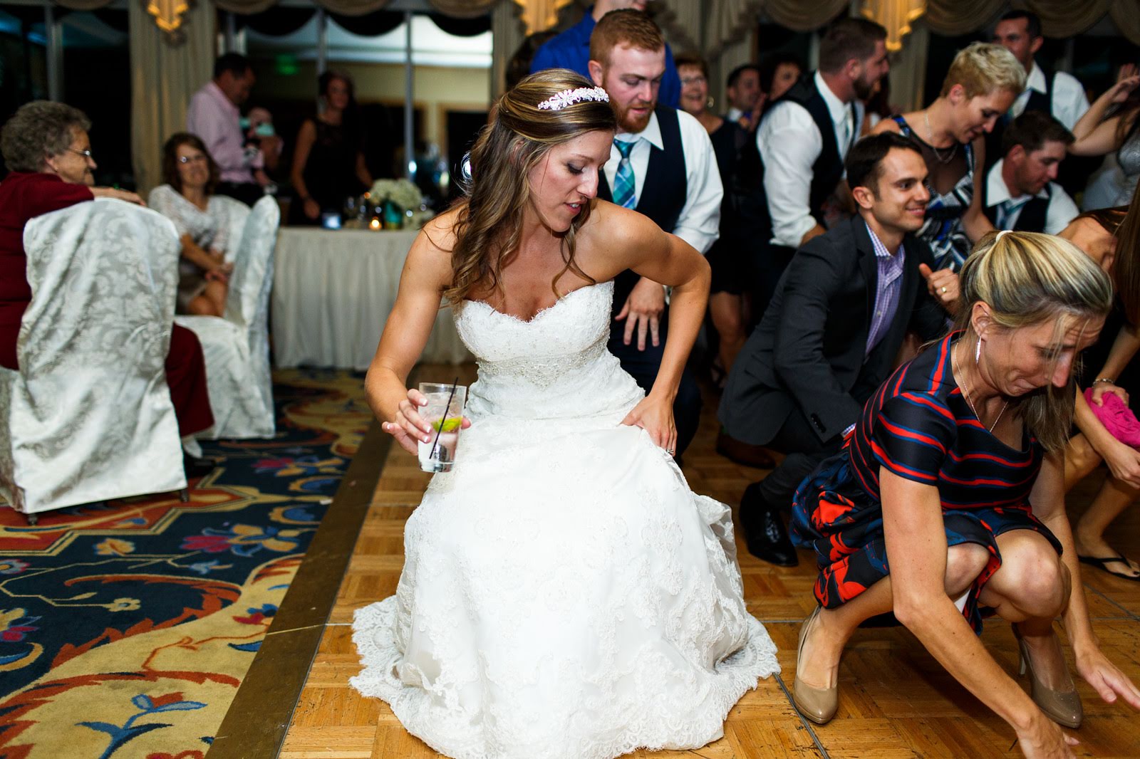 Bride in a strapless lace gown dancing low with guests at a country club reception