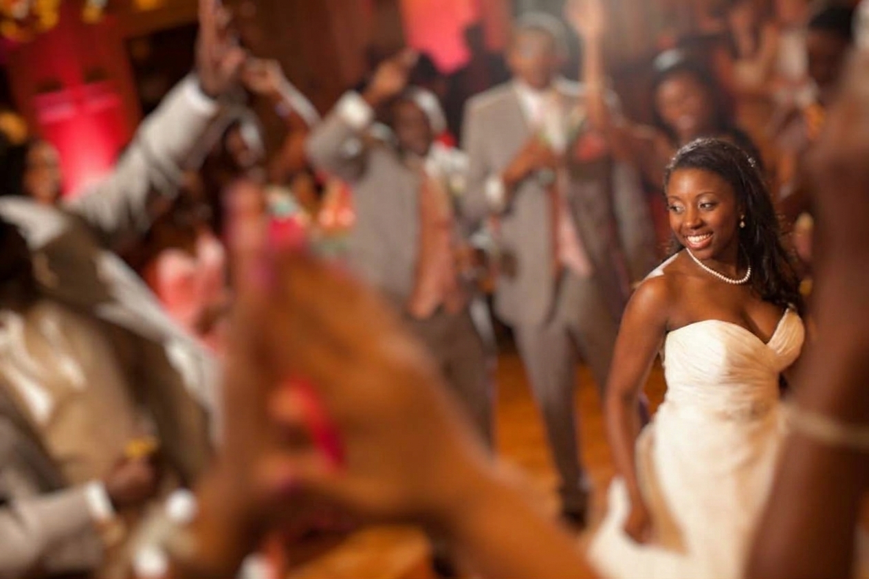 Smiling bride dancing on the reception floor as cheering guests clap around her