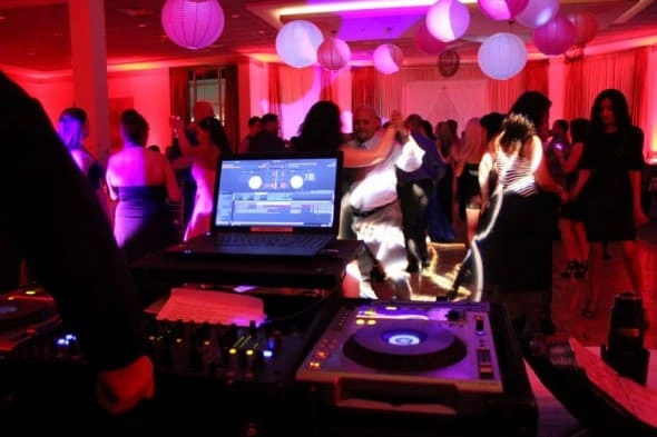 MusicMasters DJ gear in the foreground with students dancing under pink uplighting