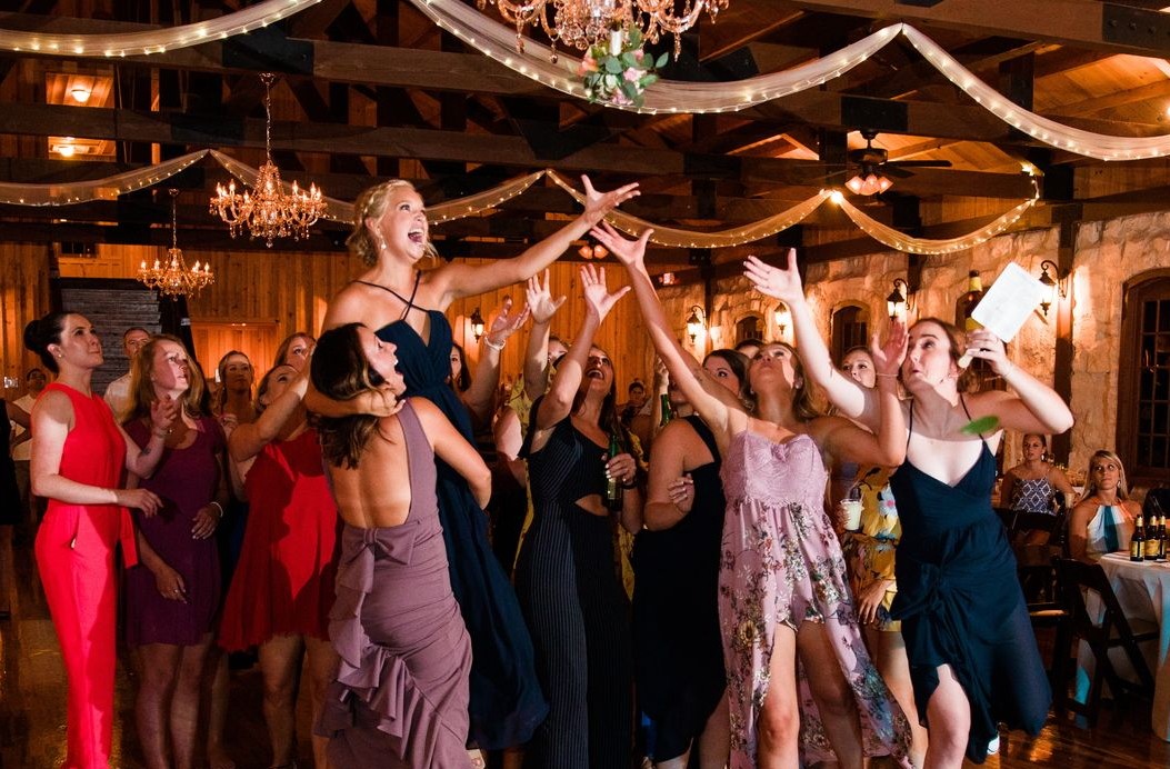 Guests reaching for the bouquet at a wedding reception