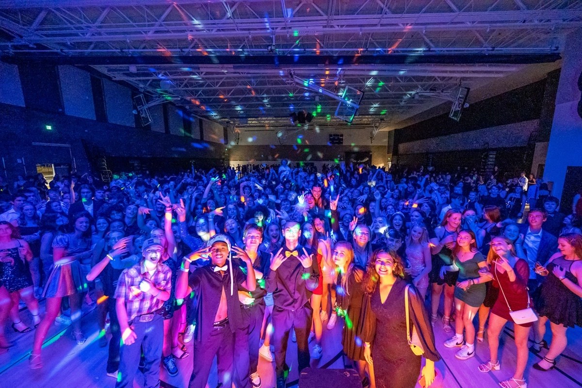High school students dancing together under coloured lights at a school dance