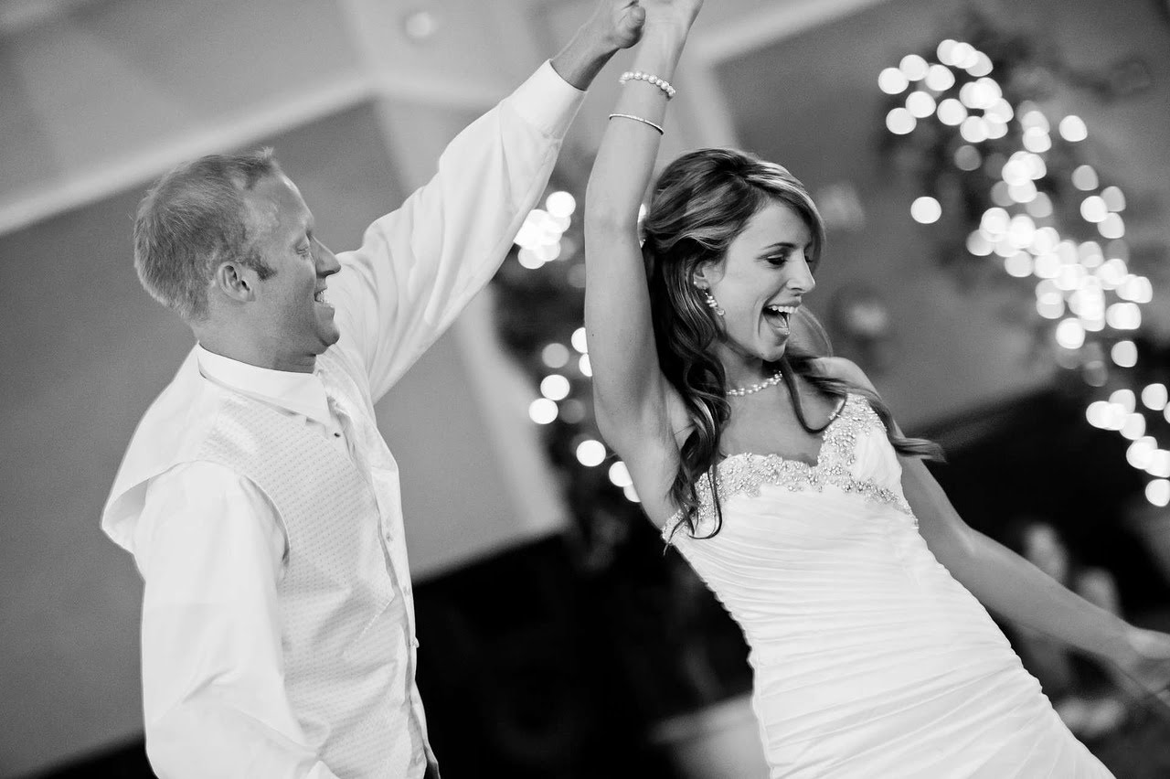 Bride and groom celebrating on the dance floor with hands raised
